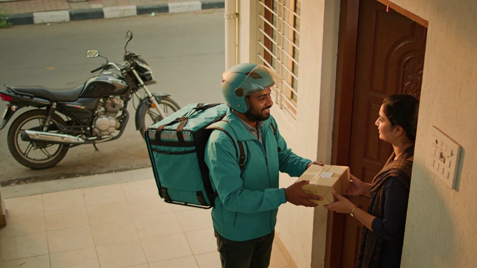 Delivery rider handing a package to a customer at an apartment doorway