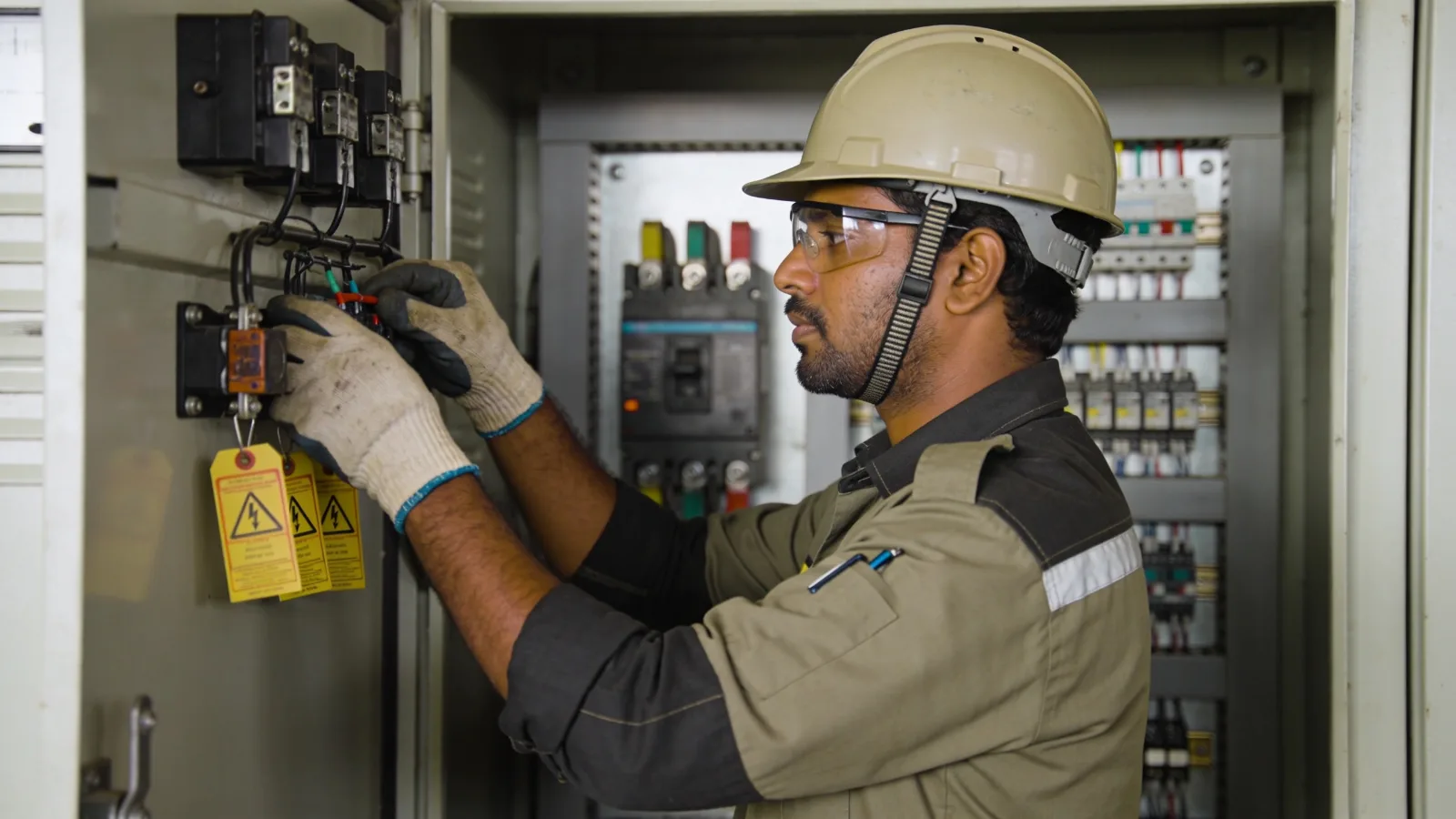 Electrician working inside an open control panel with lockout tags applied