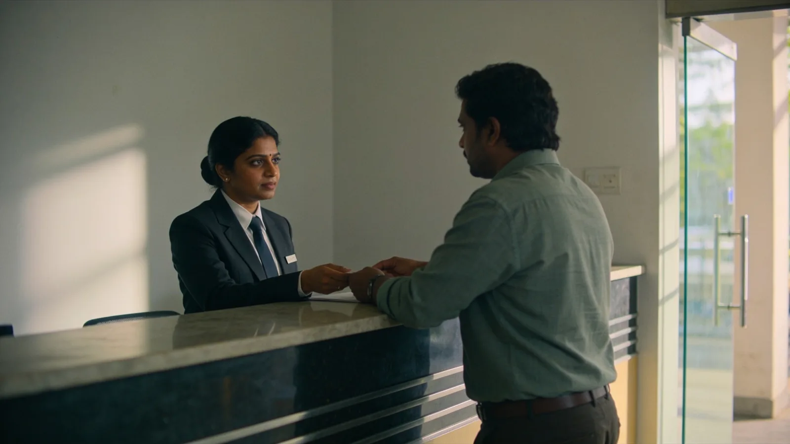Receptionist attending a visitor at a corporate front desk